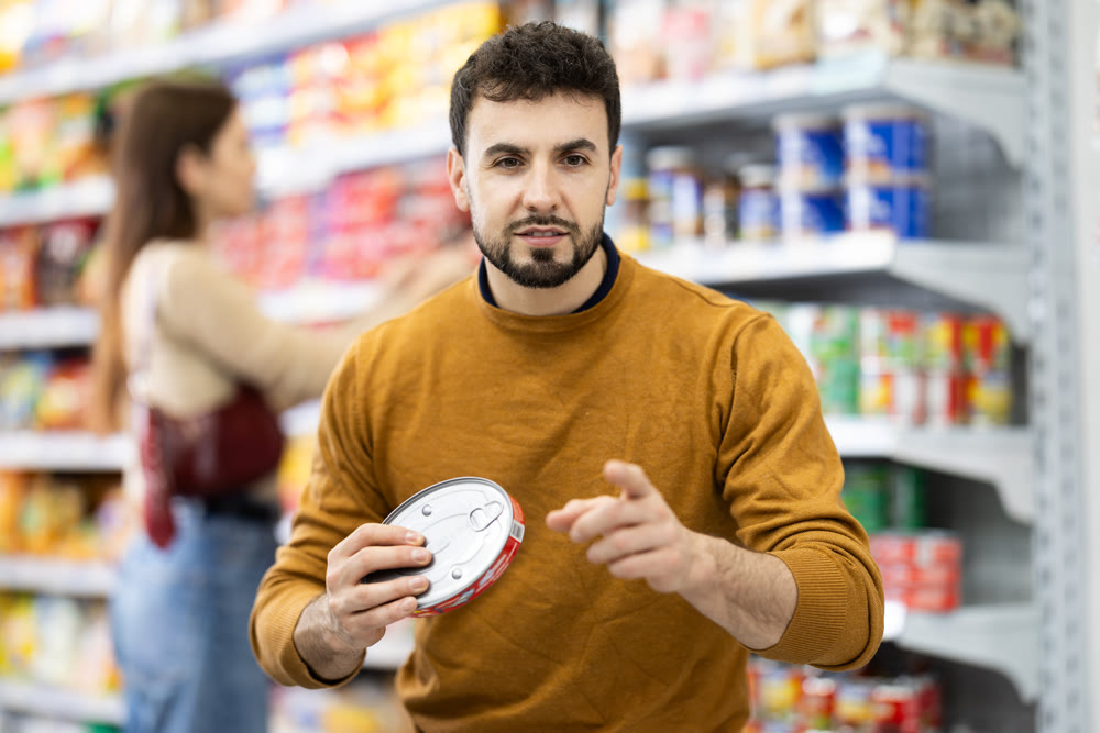 Man in supermarket search and select product tin can
