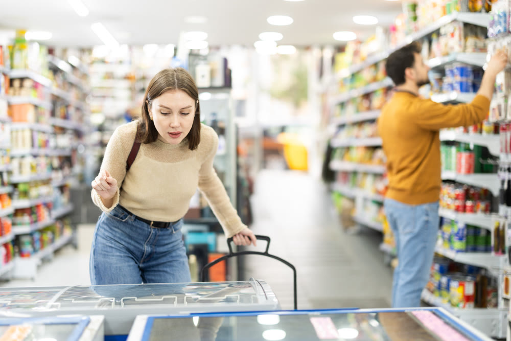 Young woman choosing frozen food in grocery store