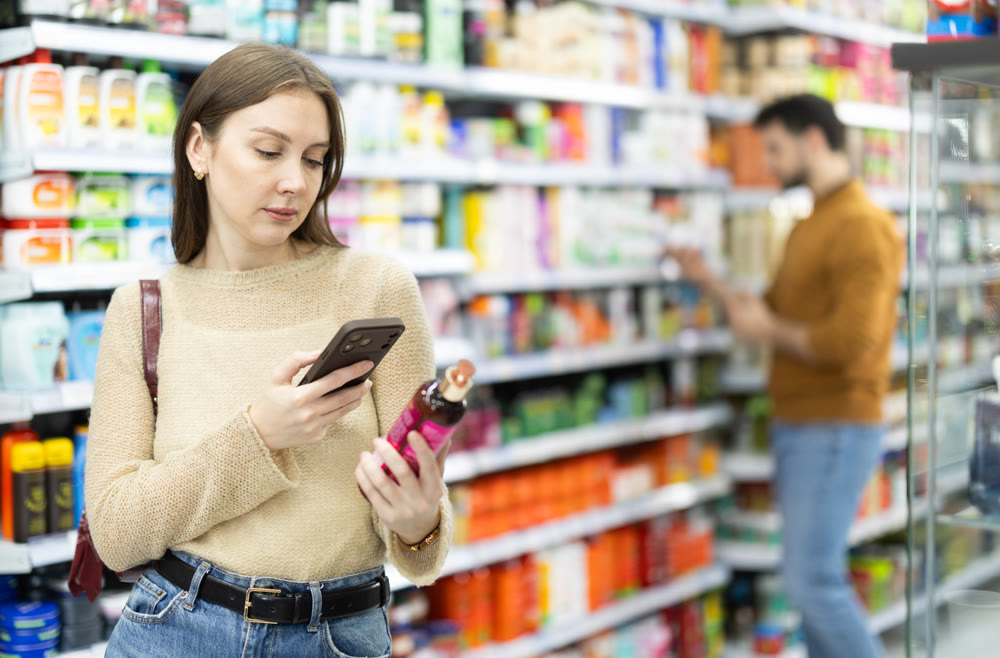 Woman get acquainted with good, scan QR code, take reading label using phone camera in shop