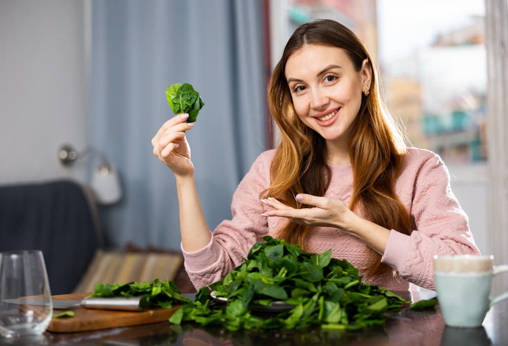 Young woman sorts fresh spinach
