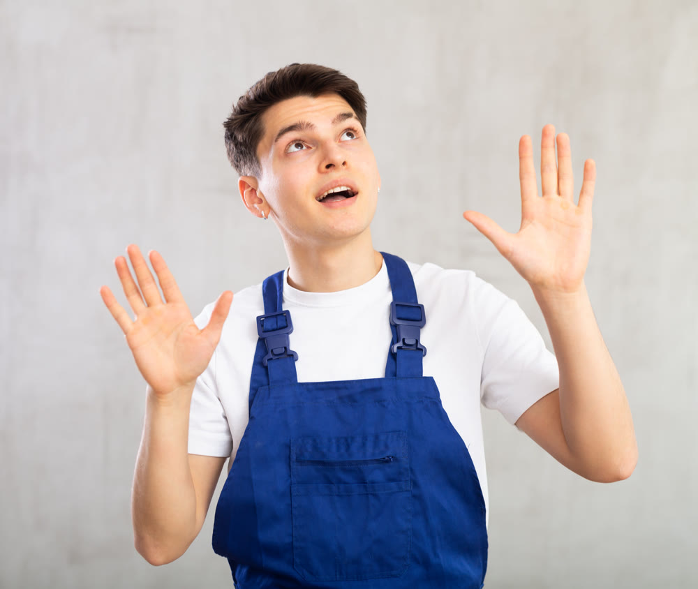 Young experienced worker in blue jumpsuit is actively gesticulating, looking up to right