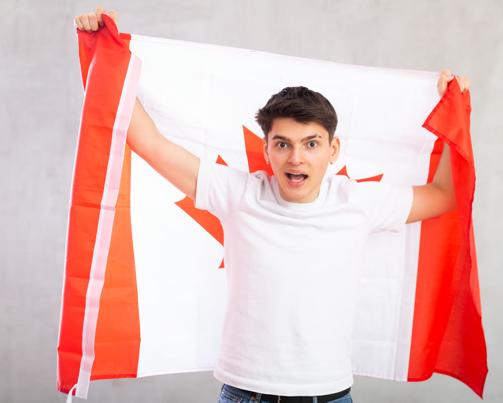 Surprised young guy holding Canada flag