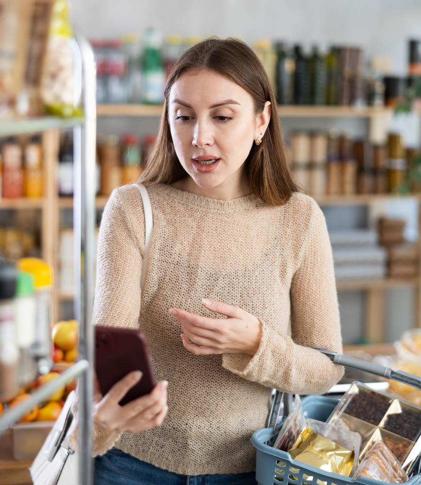 Woman engrossed in video call on phone while shopping in grocery store