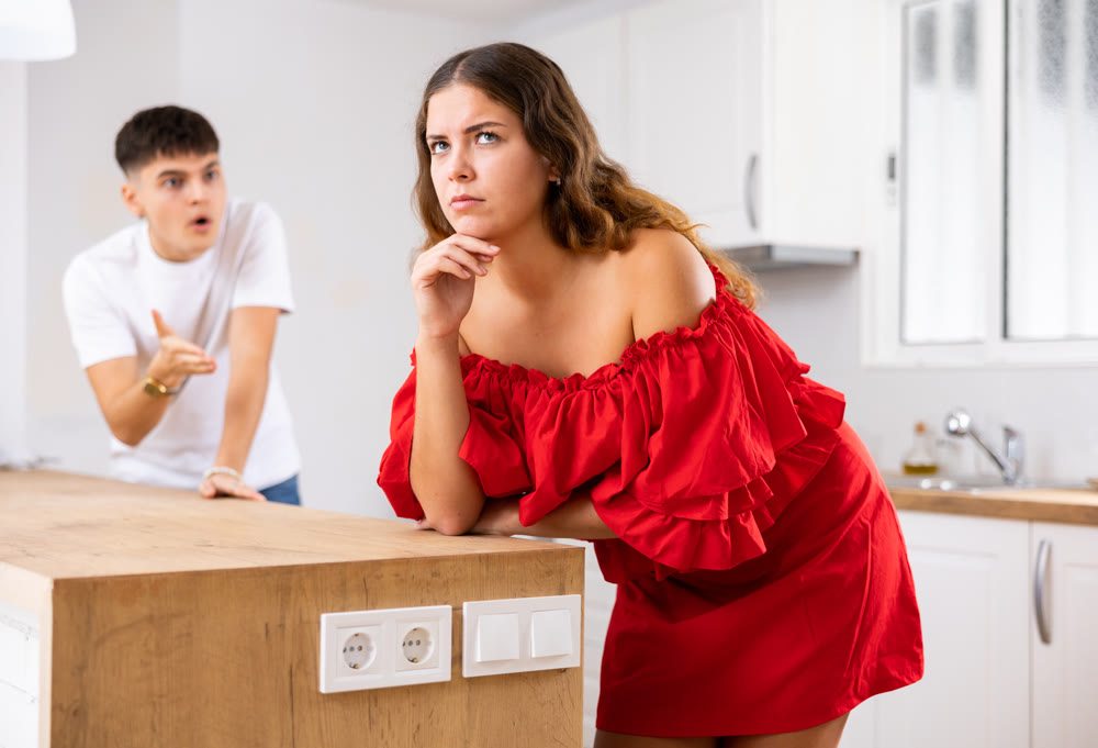 Portrait of a frustrated young woman, at whom her husband swears in the kitchen