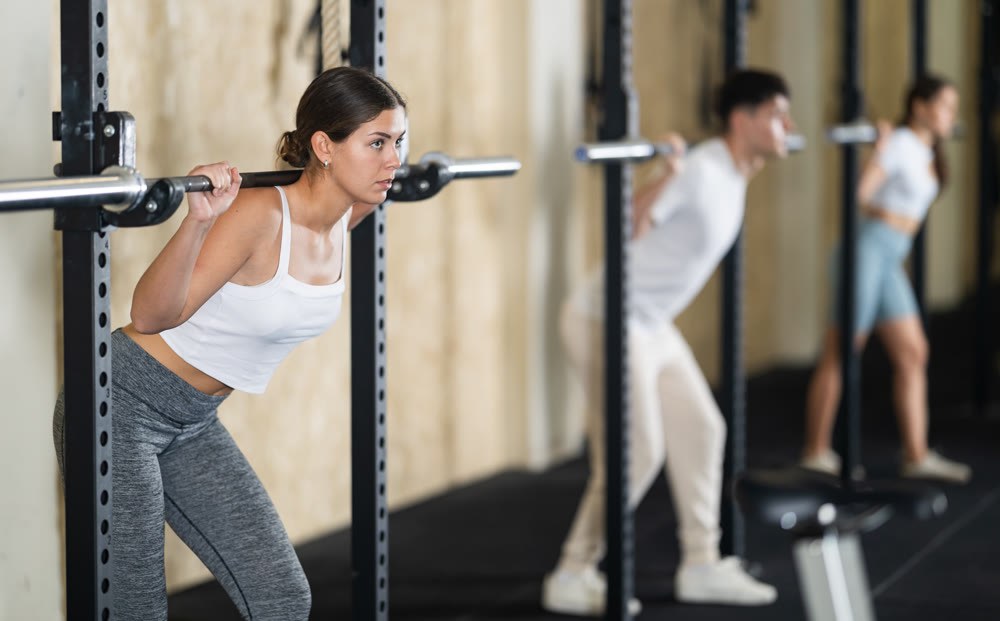 Young woman training with barbell in gym