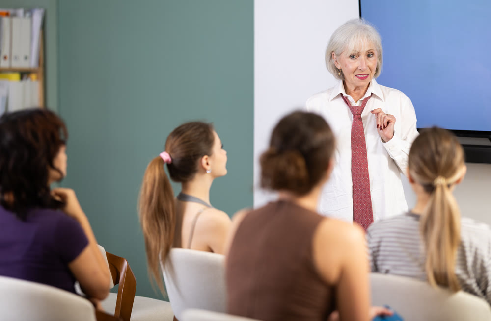 Senior woman coach speaks to audience of listeners, carry out lecture.