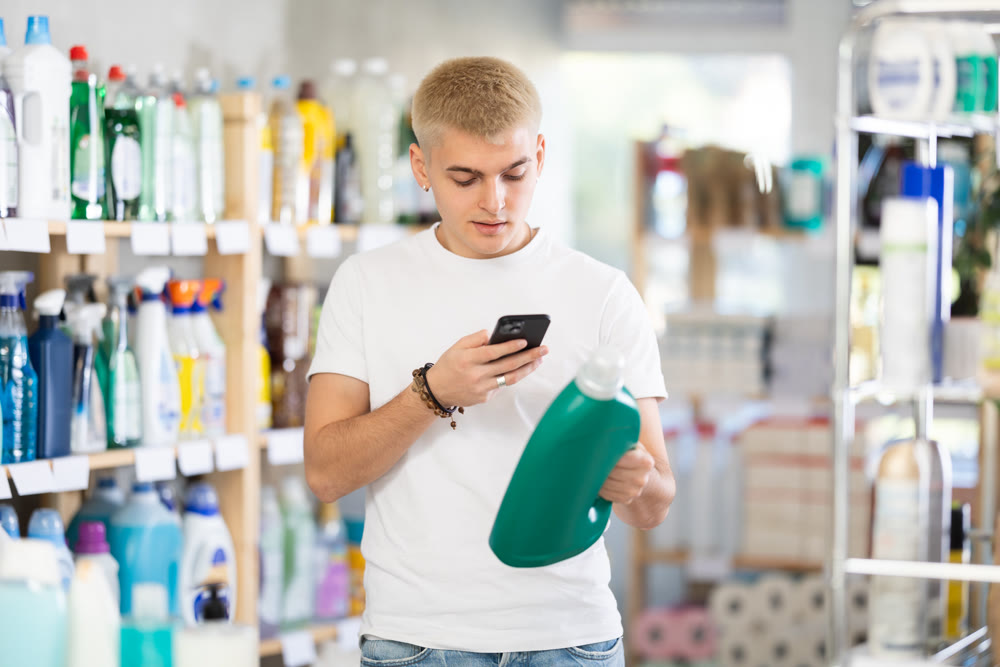 Checking expiration date of detegrent - male shopper scans QR code on label of detegrent using smartphone