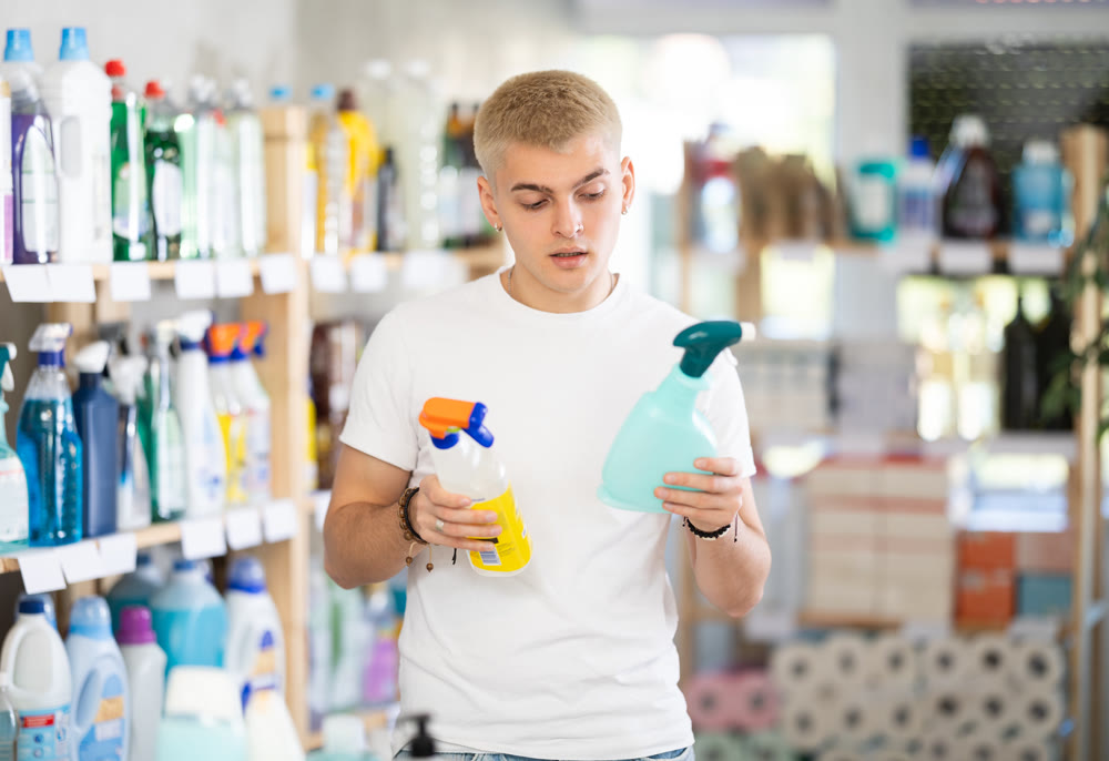 Male shopper carefully selects a spray glass cleaner for windows in home