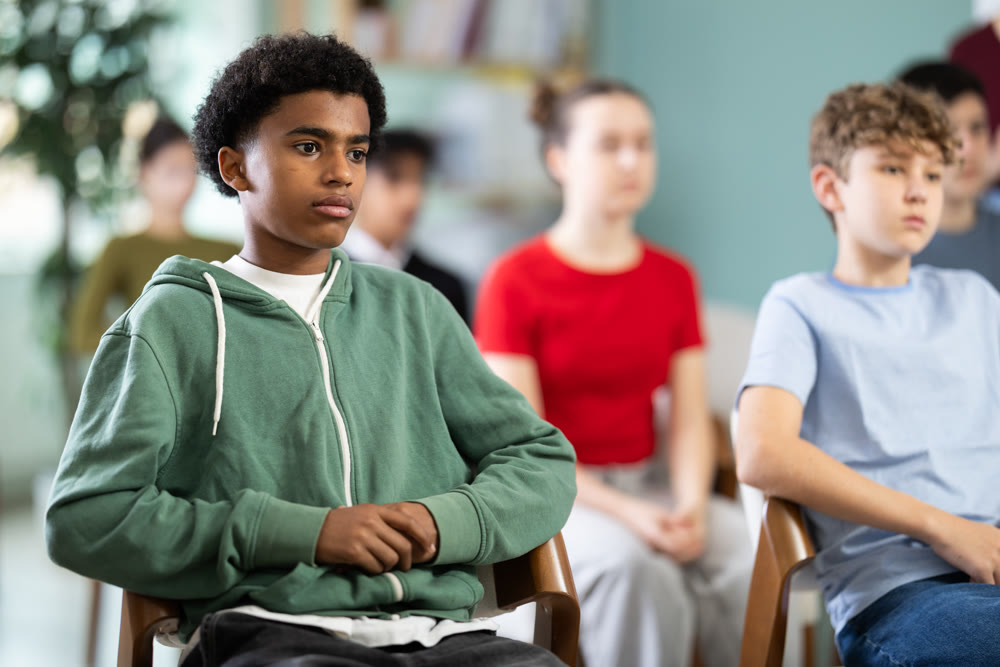 African American teen boy attendee group class and listen to lecturer.