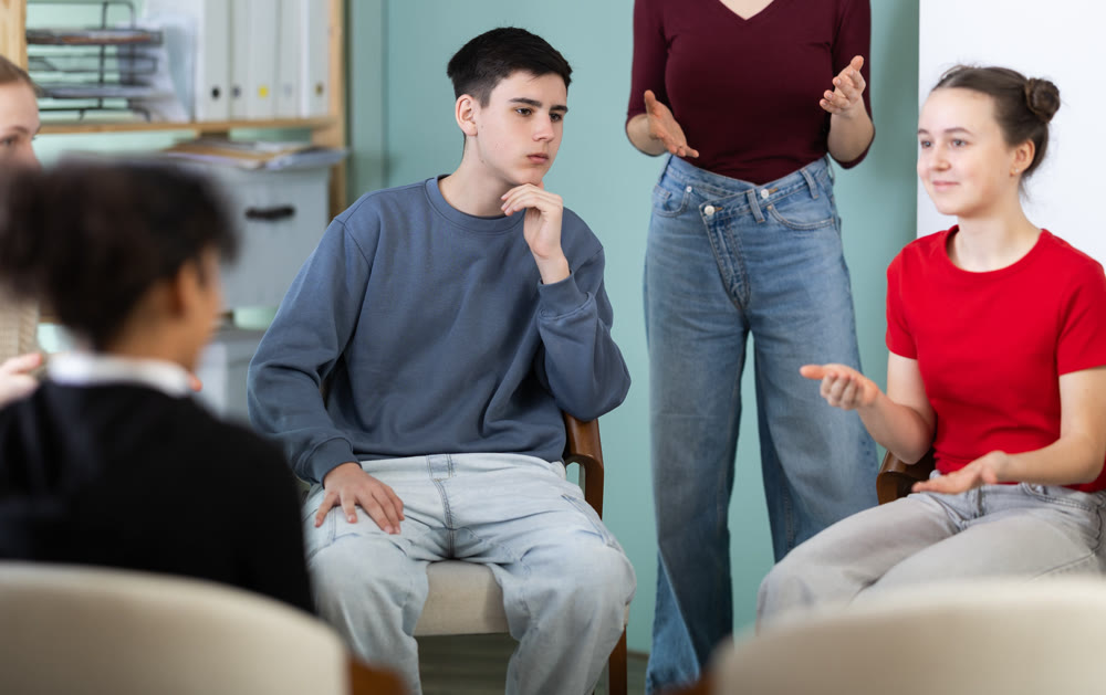 Group of boys and girls sits in a circle in the classroom