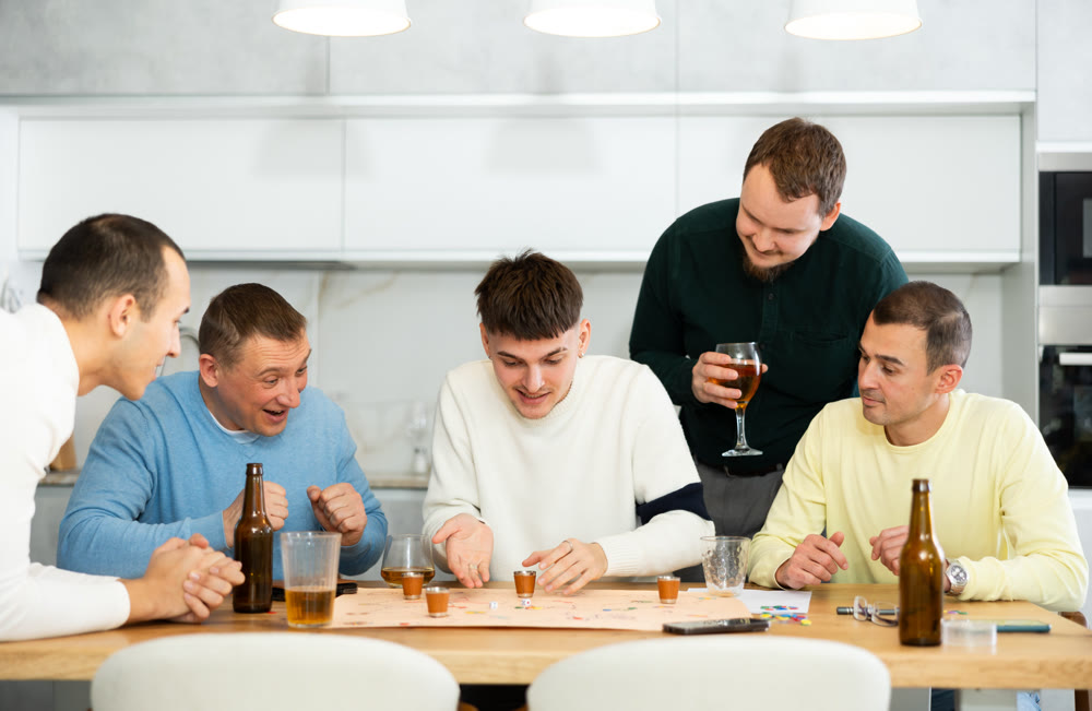 Male friends playing fun drinking board game at bachelor party