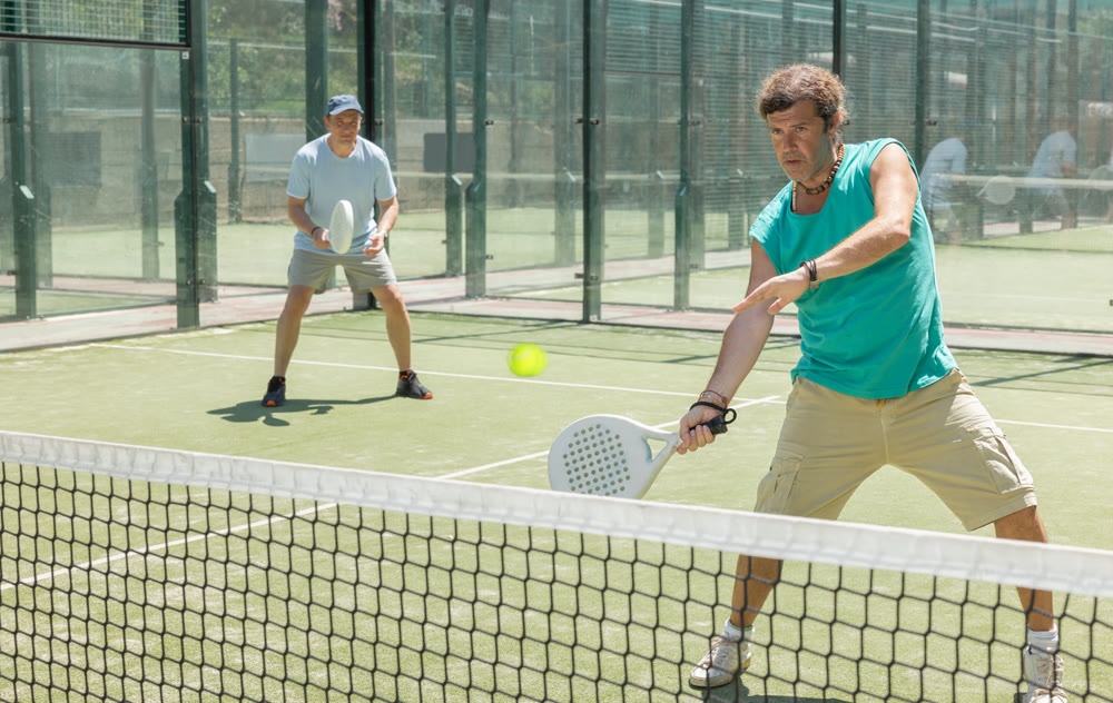 Two adult men playing doubles padel
