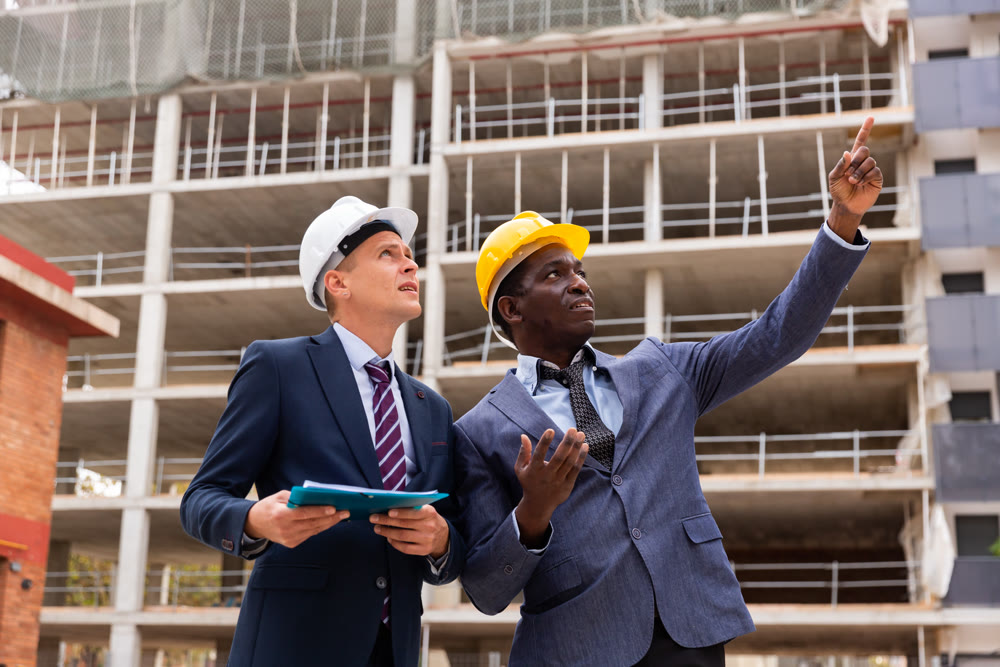 Two architect, civil engineer or building contractor colleagues on construction site