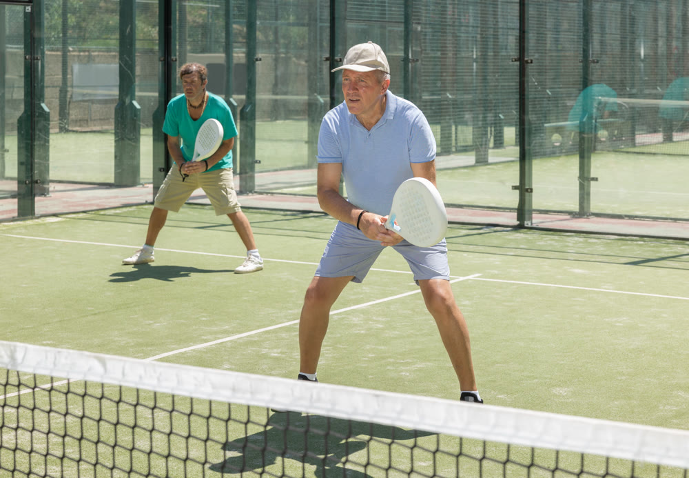 Elderly and adult men playing doubles padel
