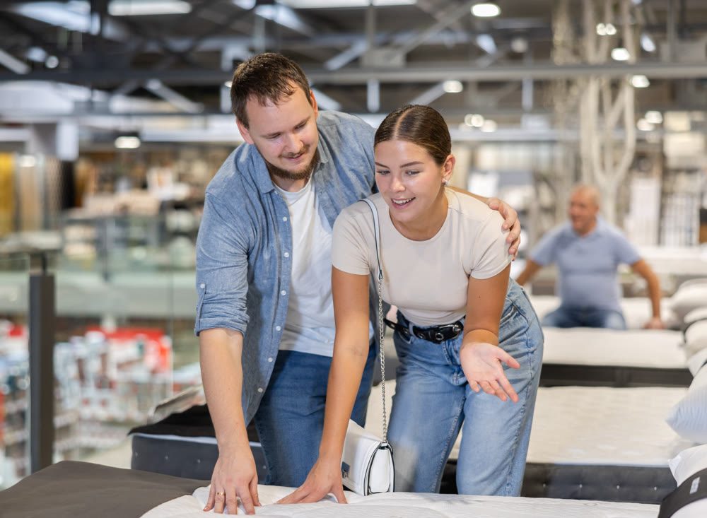 Couple man and woman choosing bed in store