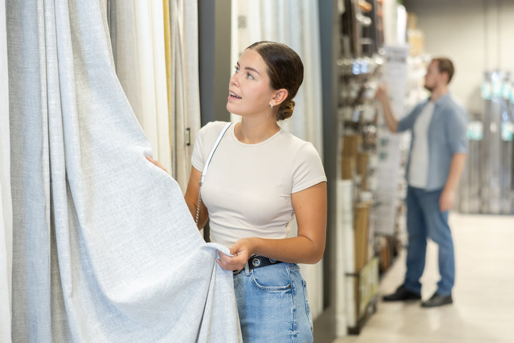 Girl touches and feels product, chooses curtains for windows.