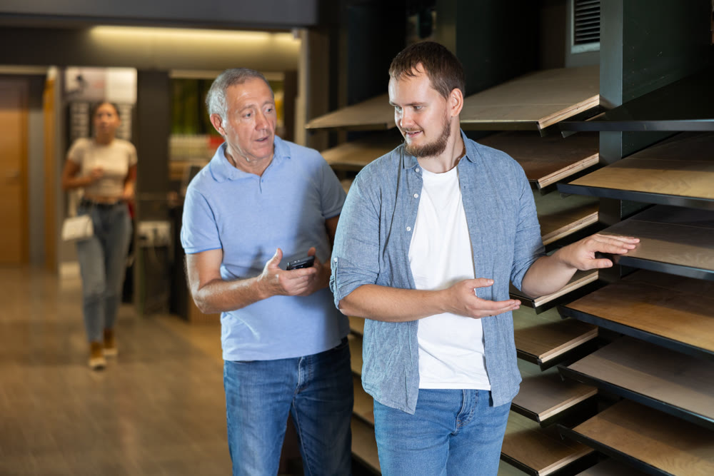 Mature man and guy son carefully examine wooden finishing material