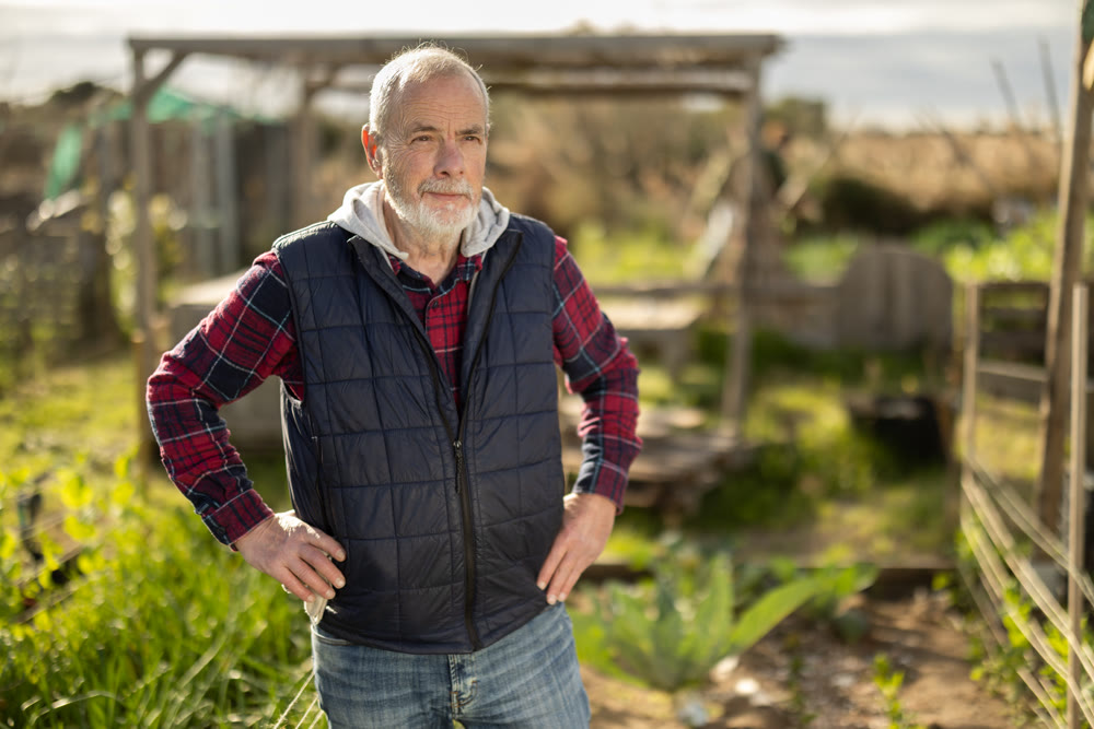 Mature man owner of plantation garden is resting standing after work and tasks