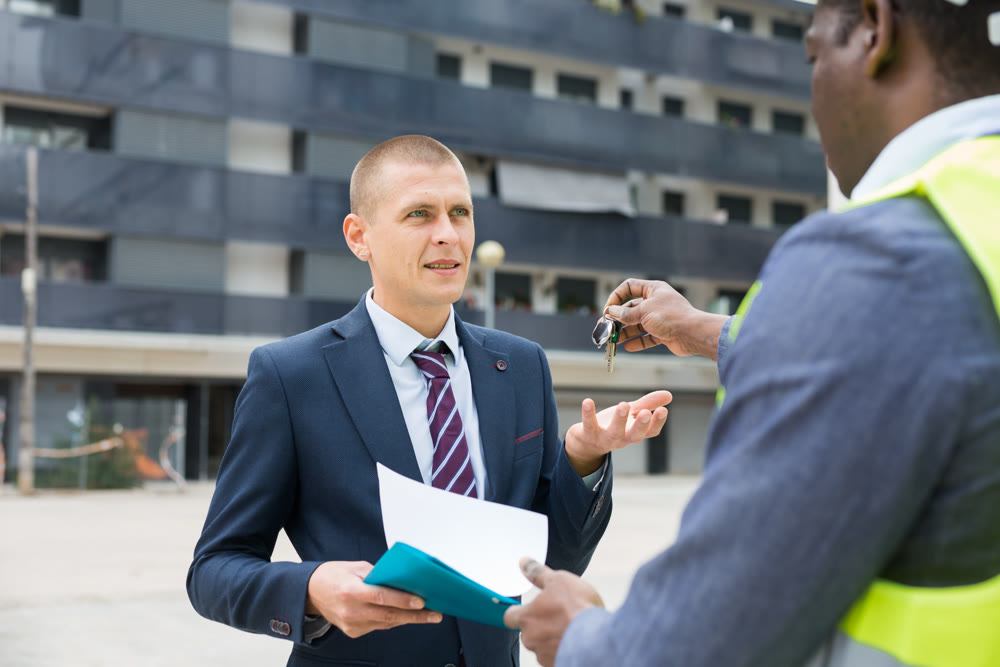 Engineer giving keys to new apartment to man