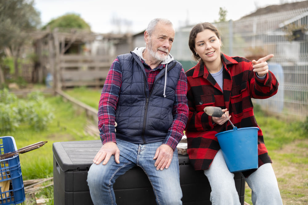 Young woman and elderly man talking in garden