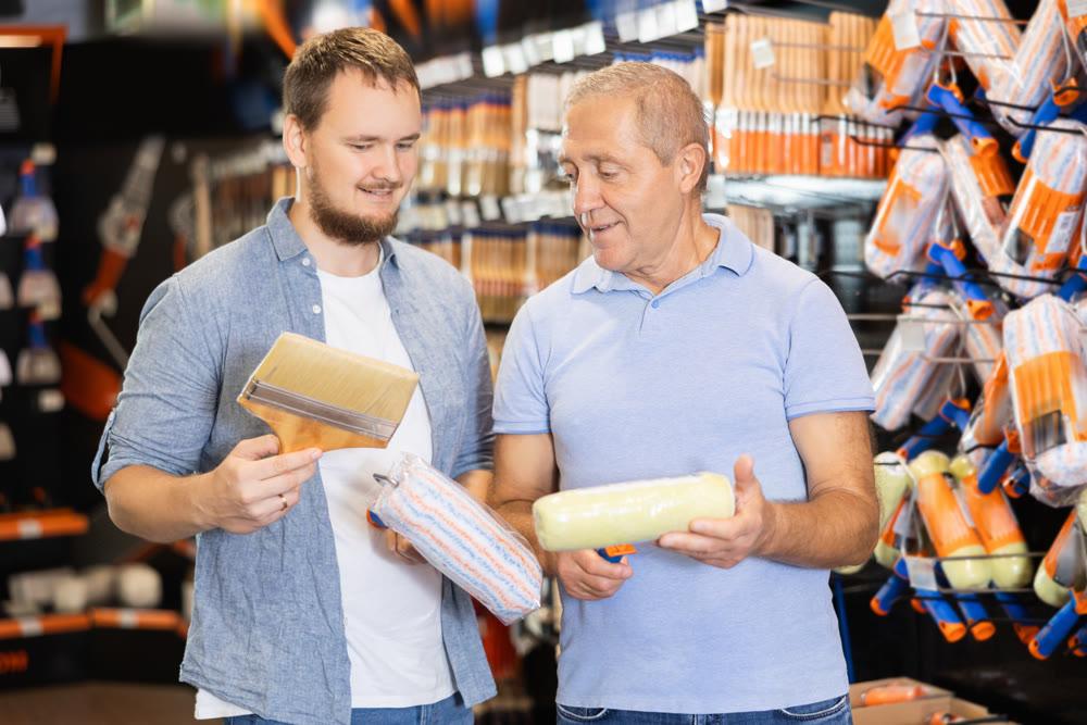 Hardware store clerk advises an elderly man on choosing the best paint roller for apartment renovation