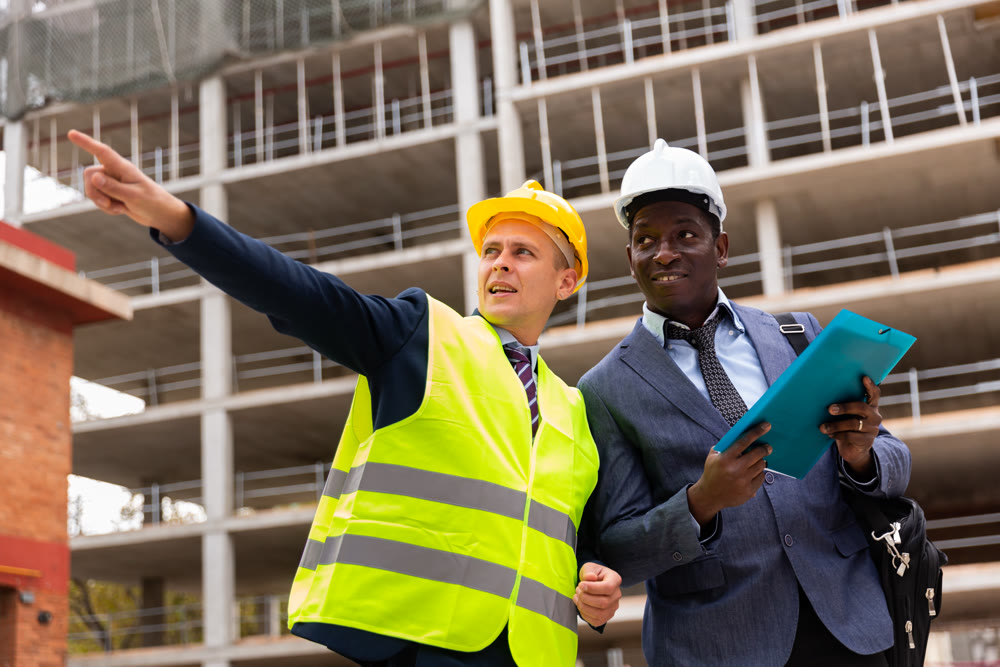 Foreman showing builder something at the construction site by pointing hand