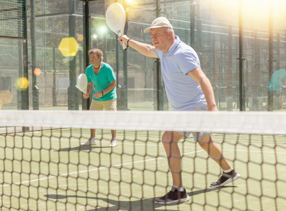 Elderly and adult men playing doubles padel