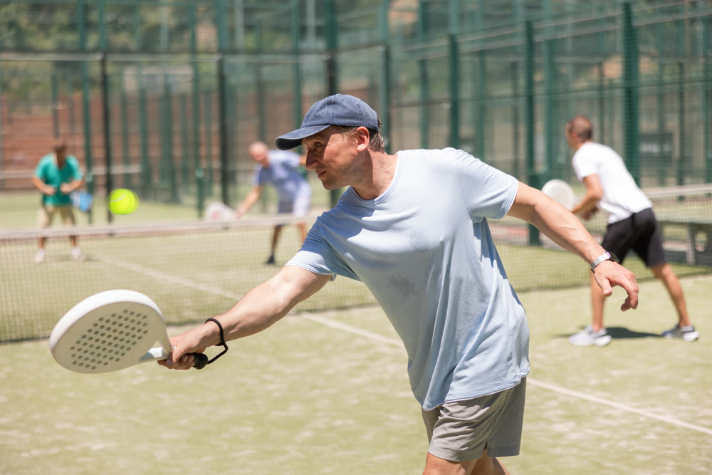 Adult and young men playing padel against two men