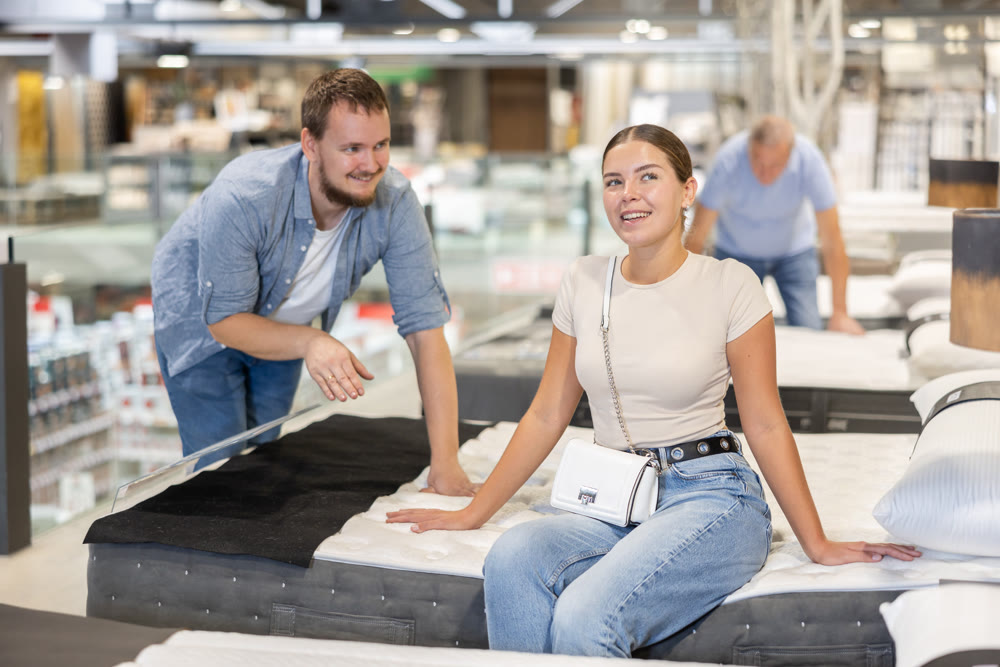 Couple man and woman choosing bed in store