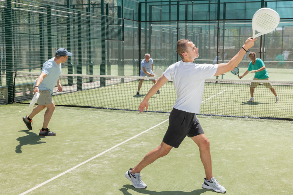 Men play padel on an outdoor tennis court. Hitting the ball with racket