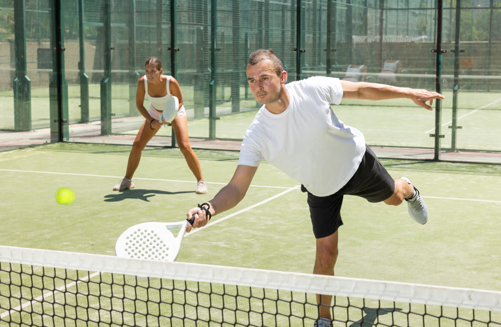 Young woman and man playing doubles padel