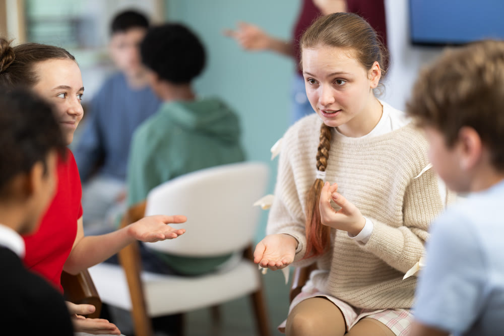 Two teams of teens, participants are negotiating, rehearsing performance, teacher watching
