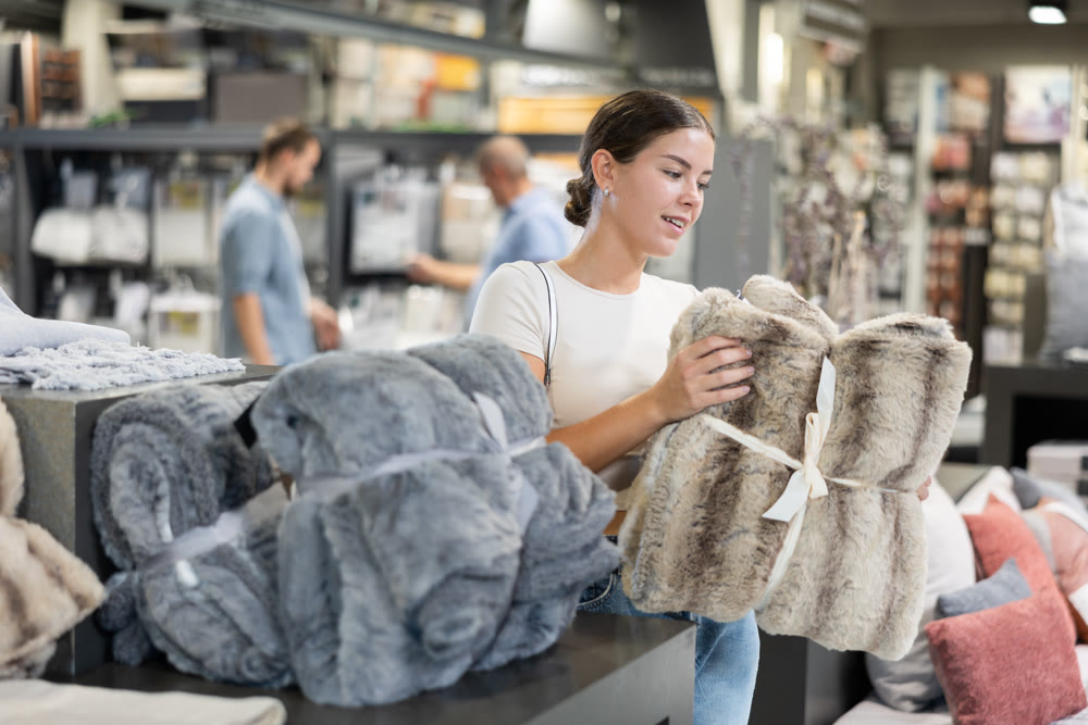 Female buyer carefully chooses warm blanket to create coziness in his apartment
