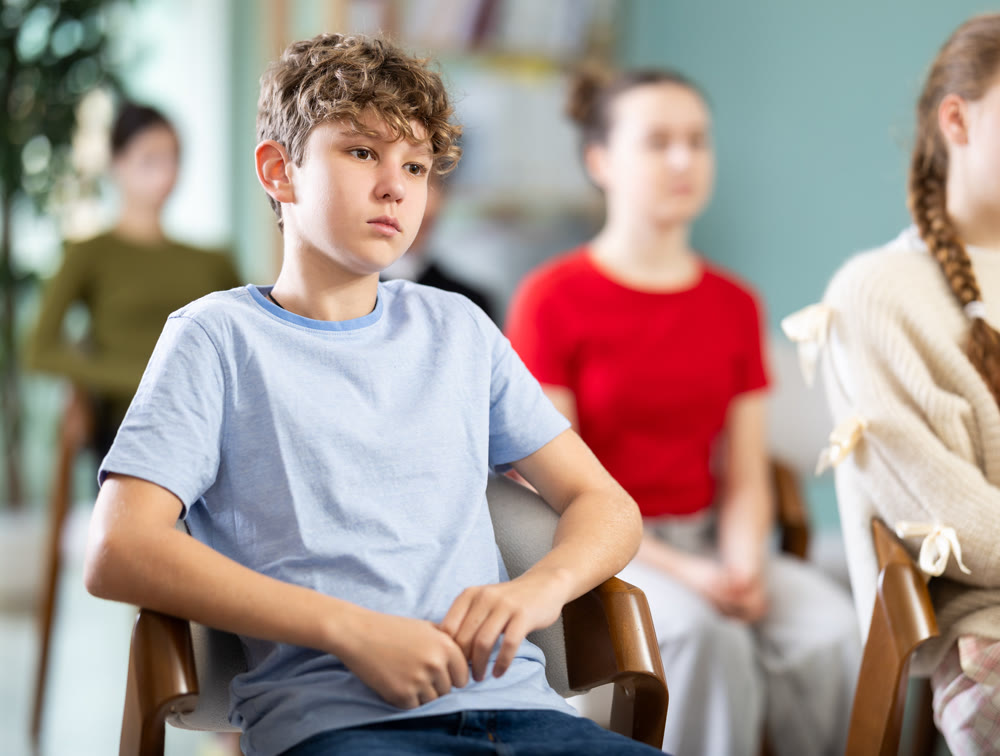 Boy sits next to his classmates and carefully looks at a lecture