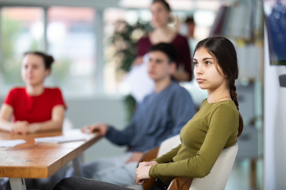 Schoolchildren teenagers sit at the table and carefully watch documentaries