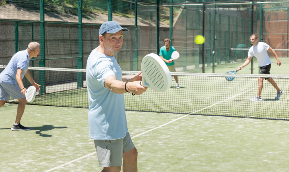 Adult and elderly men playing padel against two men