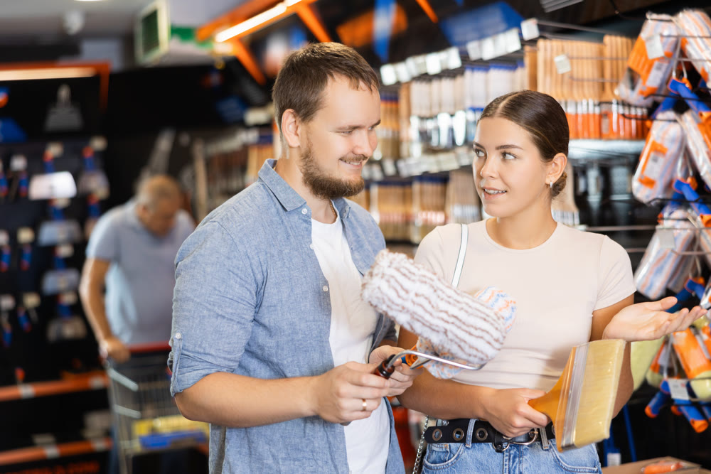 Couple man and woman choosing paint rollers and brushes