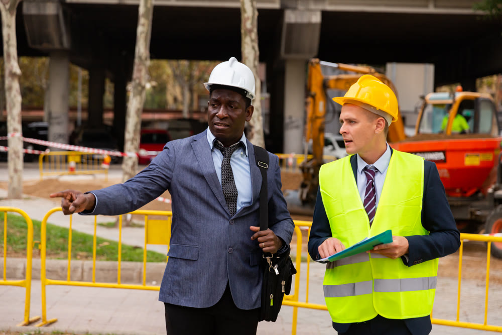Architect tells engineer where to dig a trench to lay pipe