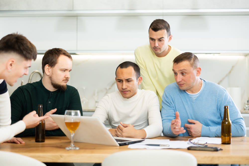 Worried male friends trying to solve problem together on laptop