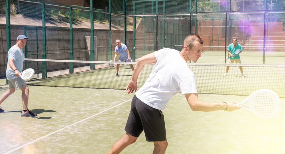 Adult and young men playing padel against two men