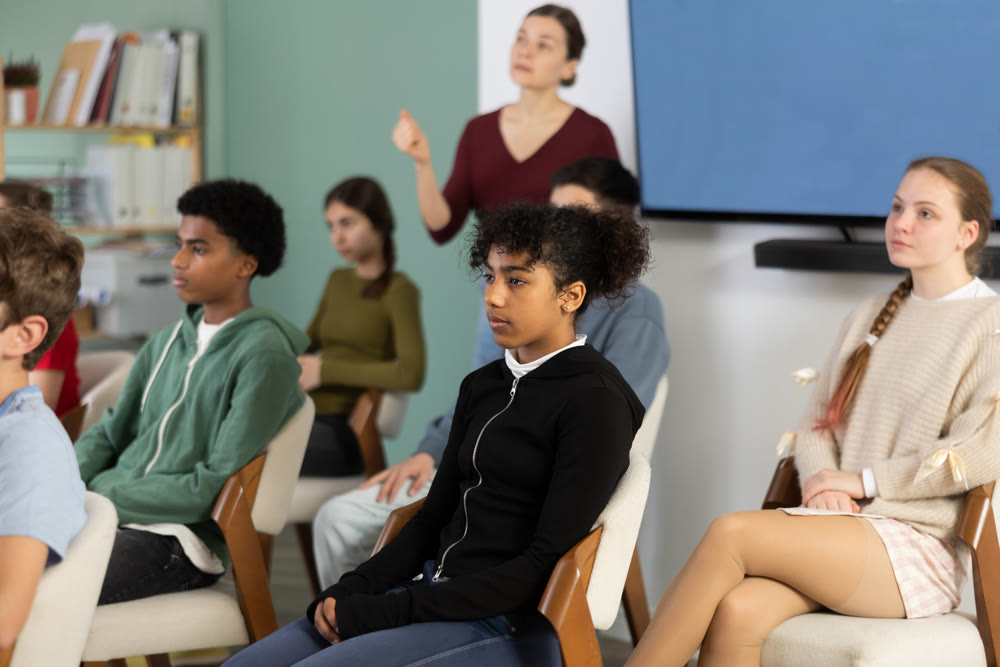 Teenage children sit in the classroom and look at the presentation
