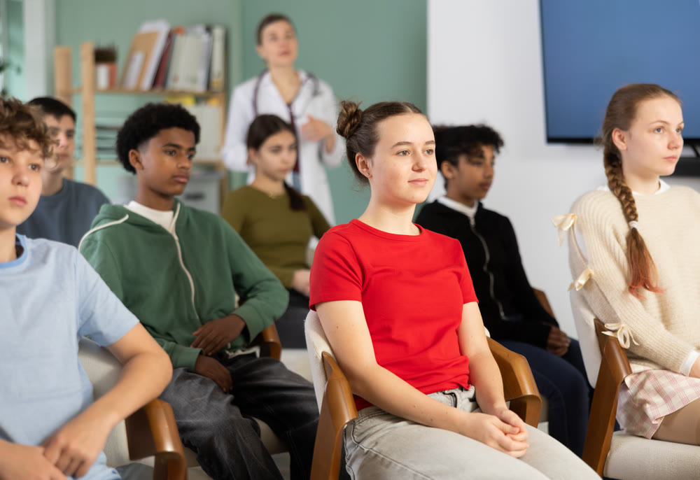 Schoolchildren carefully watch a lecture in the classroom against the background of a a doctor teacher