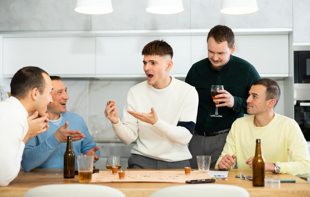 Group of cheerful men engaged in alcohol-fueled board game