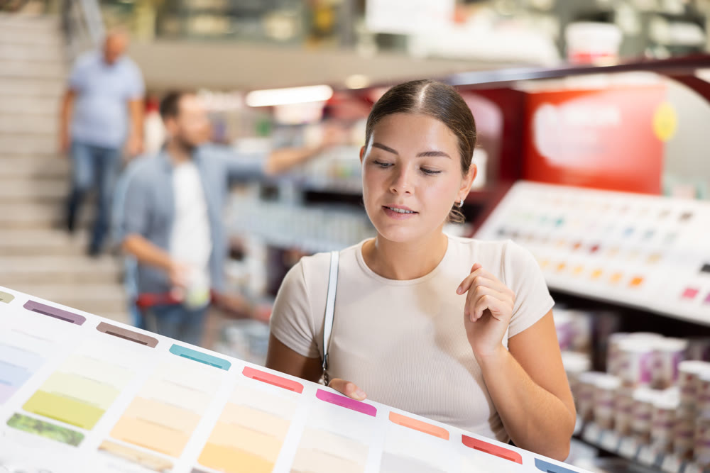 Girl examines palette, chooses color of paint for interior work in store