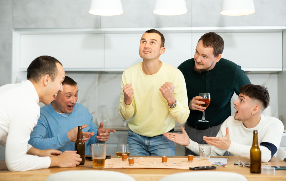 Group of cheerful men engaged in alcohol-fueled board game