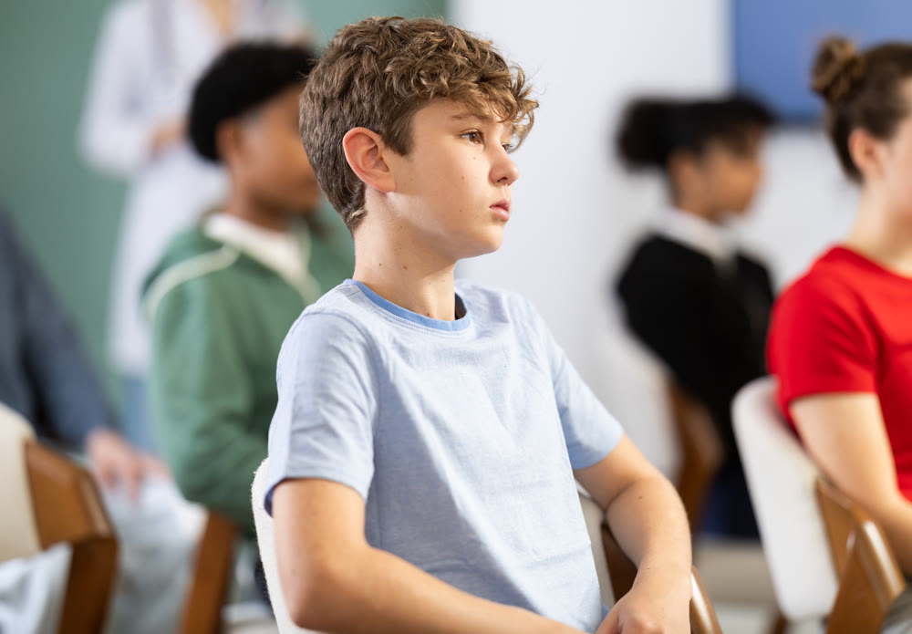 During meeting at class, teen pupil listen to lecture, doctor lecturer in background.