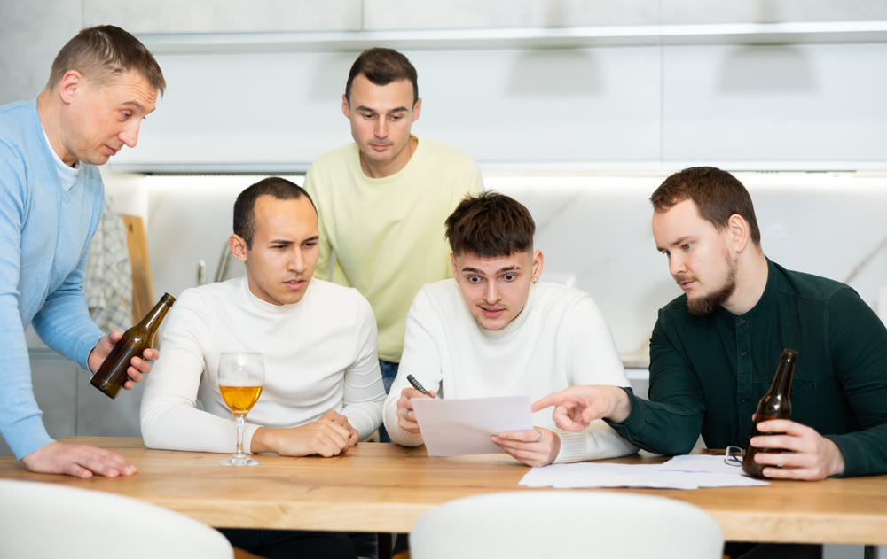 Brainstorming - male friends drinking beer and trying to solve financial problems by consulting each other while sitting at table