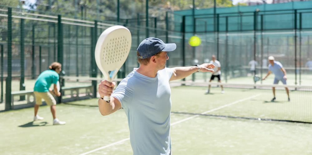 Men play padel on an outdoor tennis court. Hitting the ball with racket