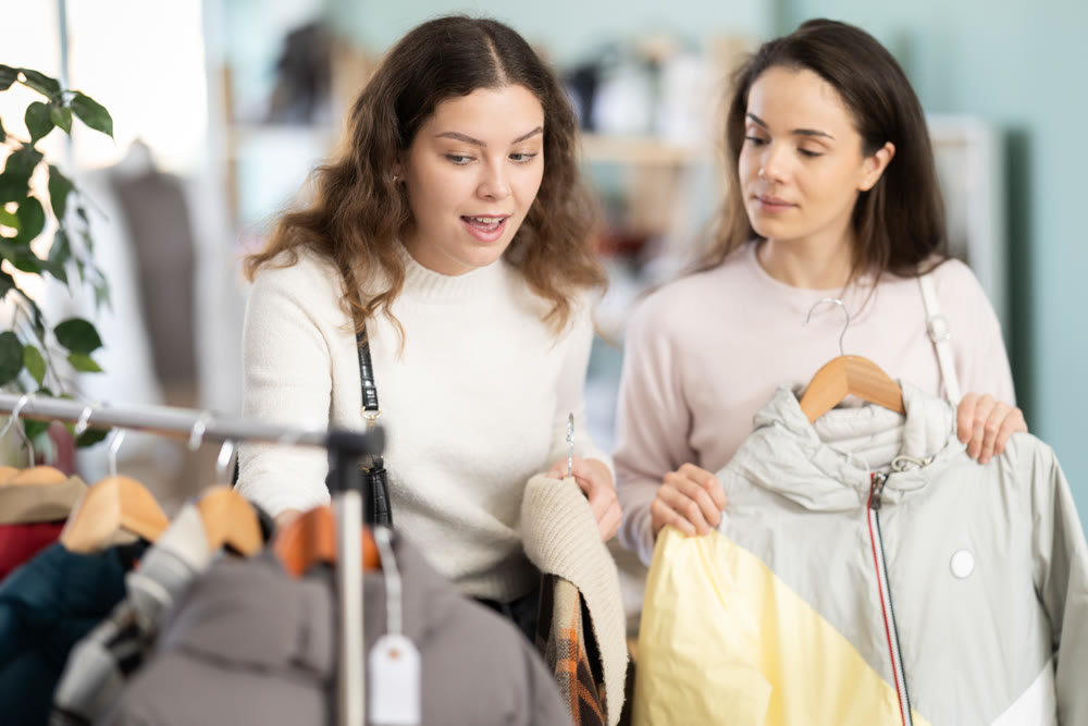 Female friends standing in the store and choosing outerwear