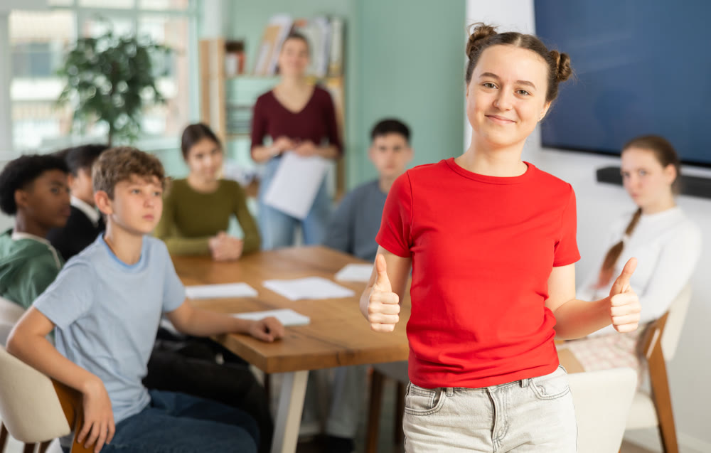 Joyful teenage girl standing in classroom